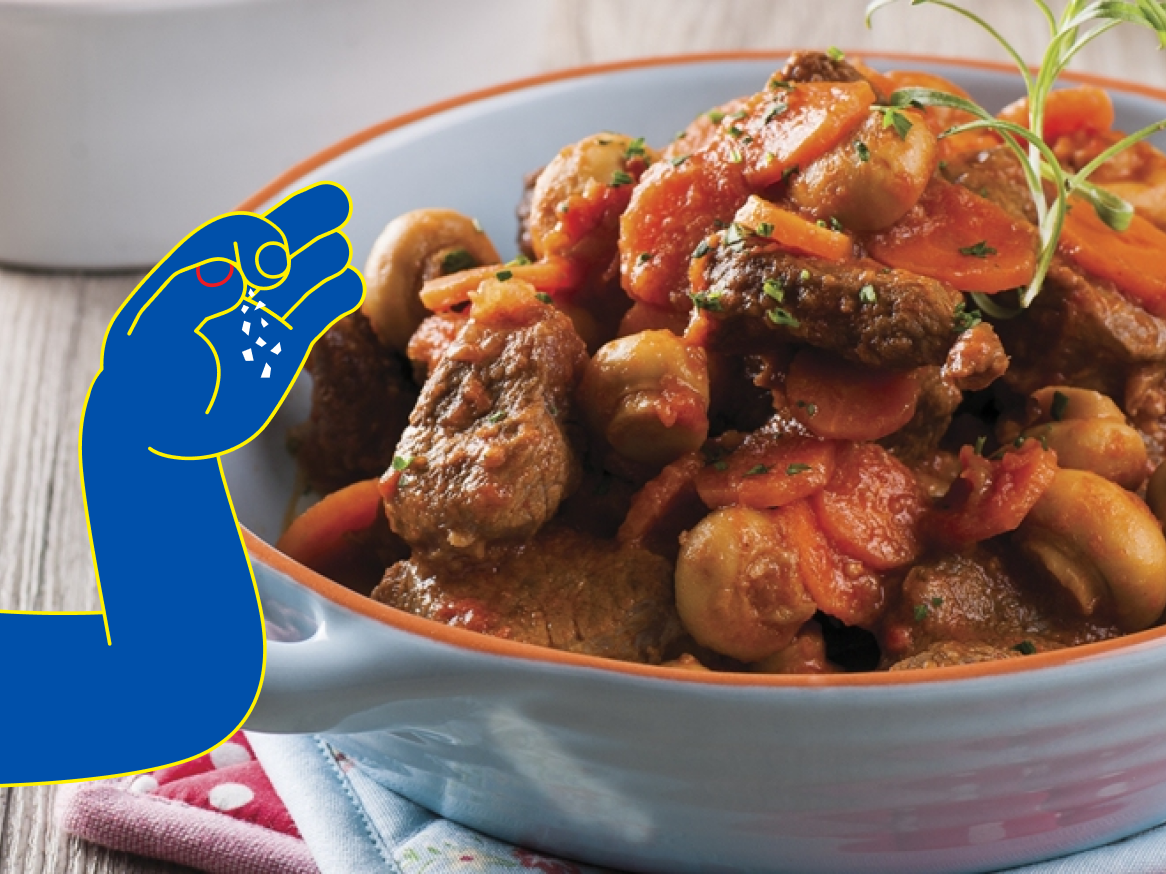 Um delicioso ensopado de carne com cogumelos e cenoura, sendo temperado com sal.