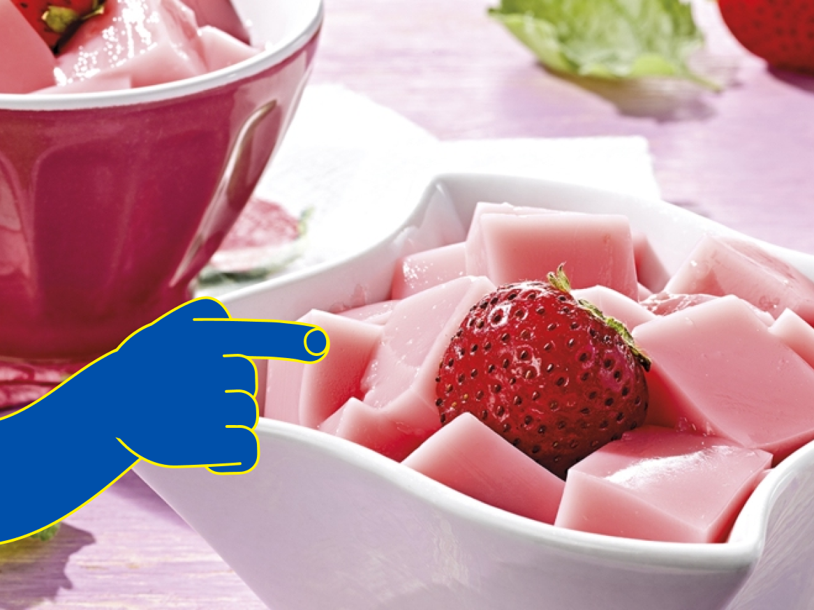 Sobremesa de gelatina rosa em forma de cubos com morangos frescos.