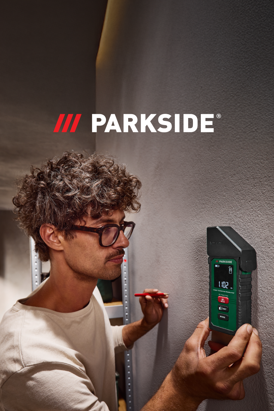Homem a usar um medidor de distância a laser Parkside para medir uma parede.