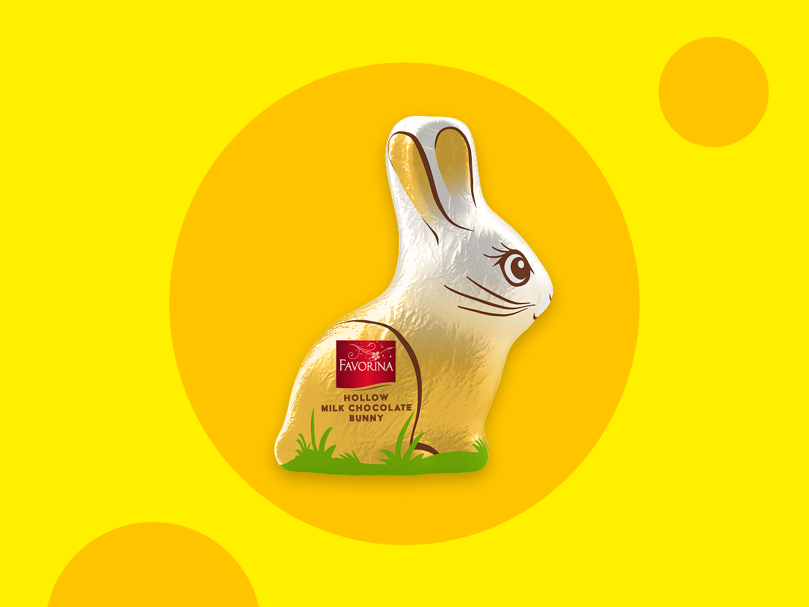 Coelho de chocolate de leite oco, dourado e branco, sobre um fundo amarelo com círculos.