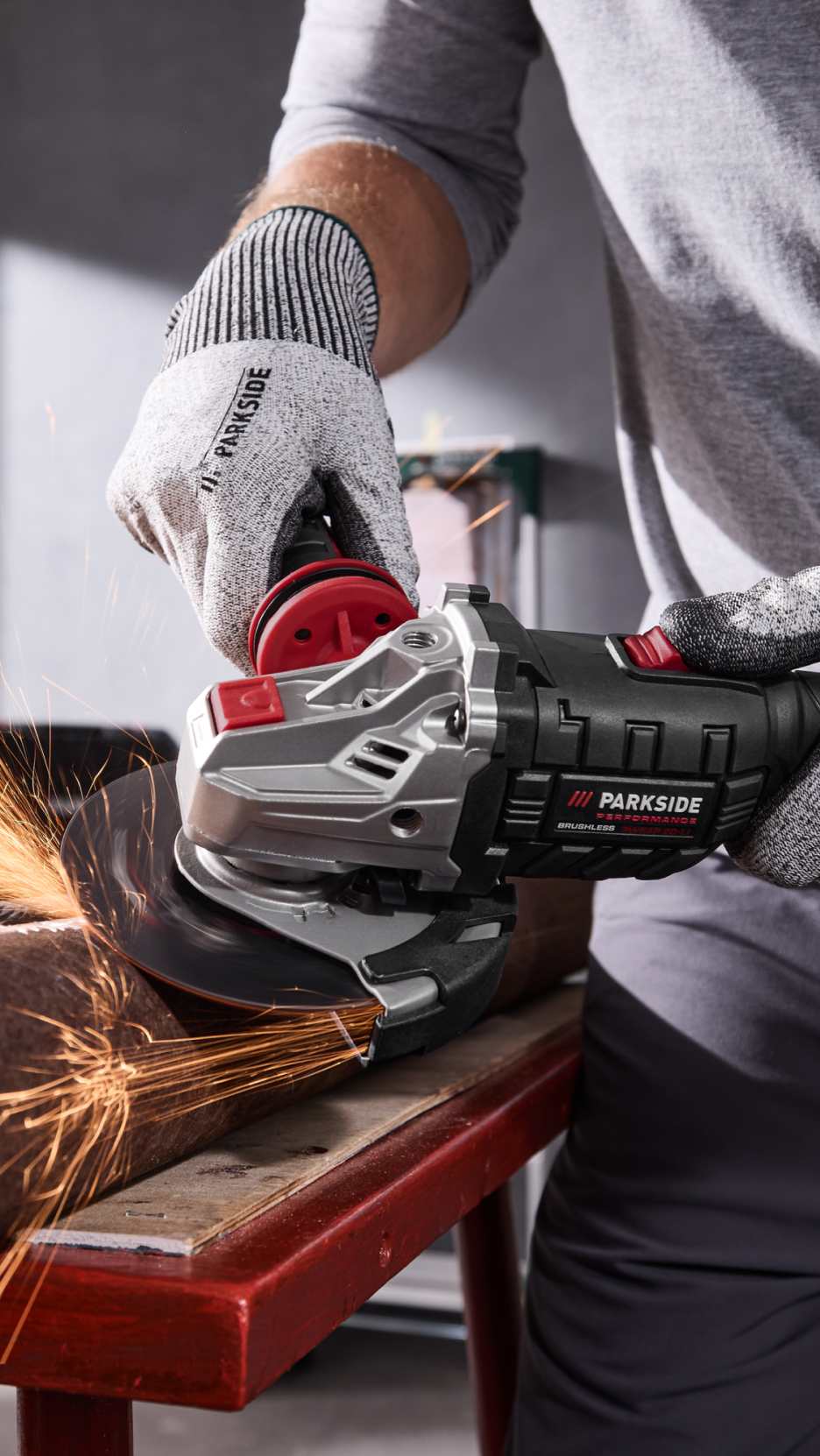 Homem a usar uma rebarbadora Parkside Performance com luvas de proteção, a cortar metal.